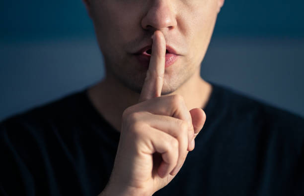 istock Secret and silence. Quiet silent shh gesture with finger on lips. Man doing expression with hand on mouth. Taboo topic, censorship or freedom or speech. Conspiracy theory. 1652925032