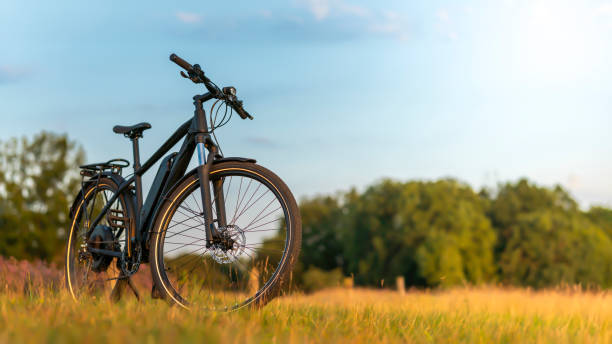 E-bike parcheggiata in un paesaggio incontaminato contro il tramonto - foto stock