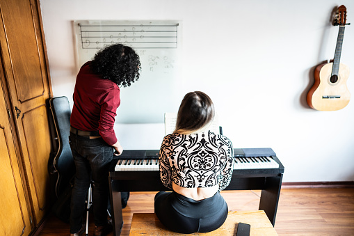 Teacher teaching music to his student indoors