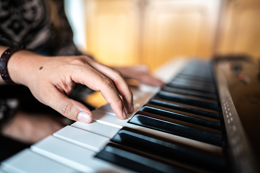 Close-up of a human hand playing music keyboard indoors