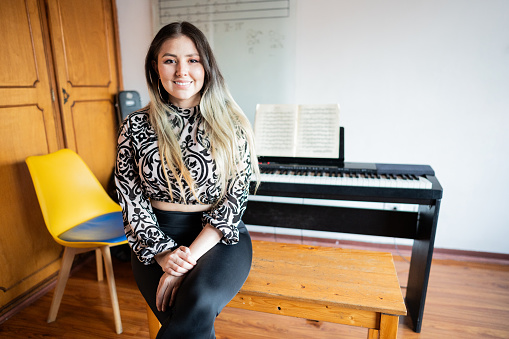 Portrait of a mid adult woman with music keyboard on background indoors