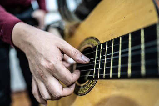 Close-up of a human hand playing guitar indoors