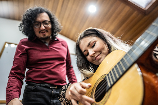 Mid adult woman learning acoustic guitar indoors