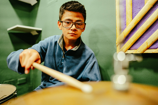 Child boy learning drum kit at a recording studio