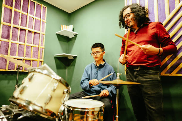 istock Mid adult man teaching drum kit to his student at a recording studio 1652935804