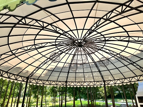 A close-up view of a wrought-iron canopy with an awning on a summer playground. The frame of the summer gazebo with decorations.