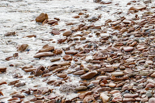 Sea surf and wet pebbles on the coast close-up