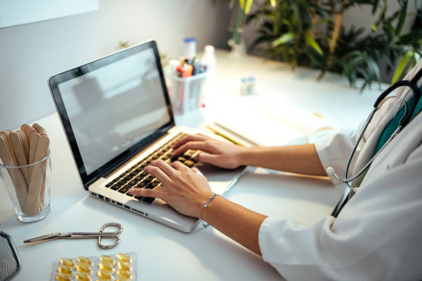 Happy female doctor working on laptop in the office.
