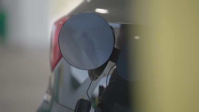 Man's hands hold gas up to car tank at rest stop station close up