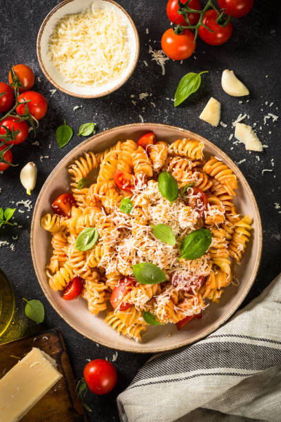 istock Italian pasta alla arrabiata with basil and parmesan cheese on dark table. 1653002169