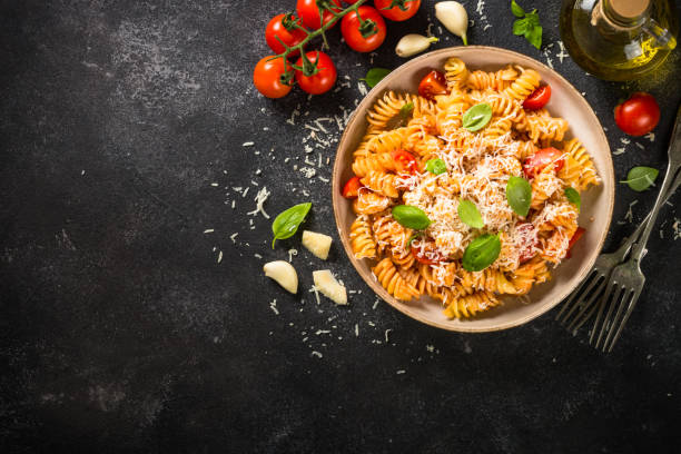 istock Italian pasta alla arrabiata with basil and parmesan cheese on dark stone table. 1653004896