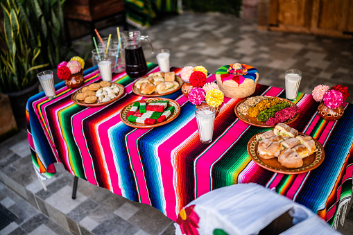 Table with decorations, food and a sugar skull piñata for day of the dead
