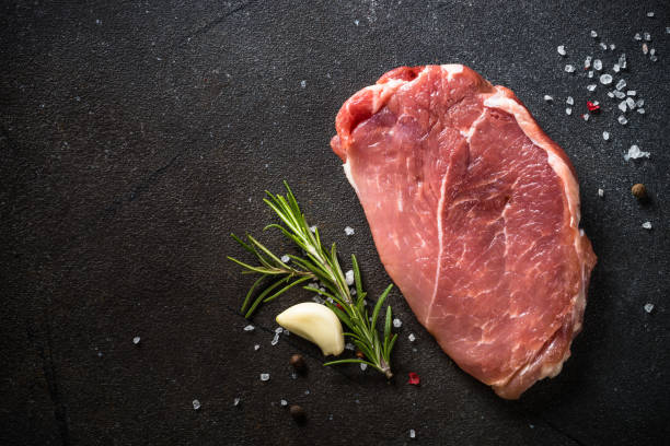 istock Fresh steak with herbs and spices at black background. 1653018701