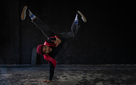 A full body of young Asian man hip hop dancer wearing clothes fashionable and tattoos on his body playing and dancing breakdance with posing showing on the stage in dark studio. Hip hop dance concept.