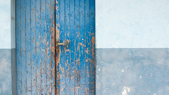 Chipping paint in blue corrugated metal door of warehouse