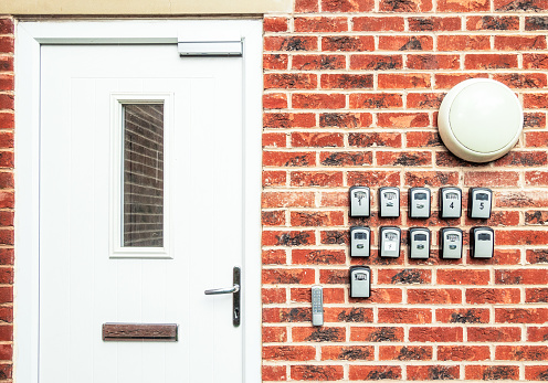 A main door to an apartment block in England, with a series of combination code lockboxes containing keys for different apartments, used for short term bed and breakfast rental.