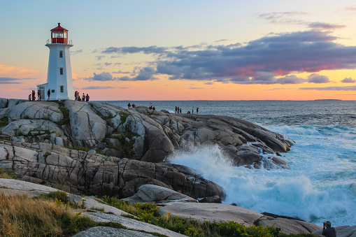 Waves crashing on the rocks by the lighthouse in the historic fishing town of Peggy’s Cove, Nova Scotia, Canada, during a sunset on the last day of August 2023.