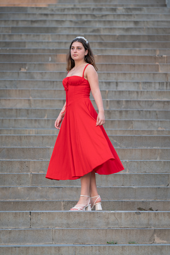 Young women in a red dress is posing on the stairs.