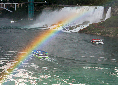Rainbow forms over tour boats and the American Falls of Niagara Falls