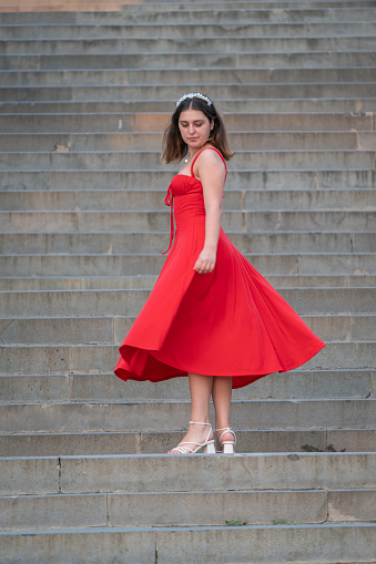 Young women in a red dress is posing on the stairs.