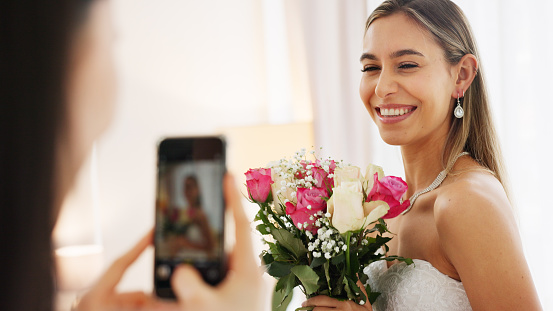 Bride, bridesmaid and wedding picture with phone with flowers or bouquet, fashion dress and an excited smile for social media. Happy woman and friend with mobile smartphone before a marriage ceremony