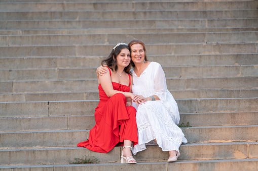 Adult mother and daughter pose for camera on street stairs
