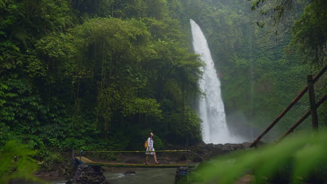 Woman standing near the refreshing waterfall on Bali