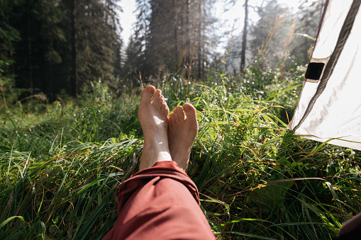 foot health, feet in nature on green grass, recreation in nature with a tent in summer