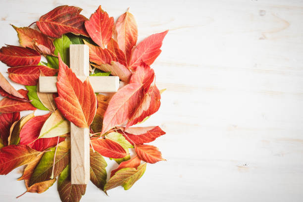 istock Wood cross with autumn leaf border on a white background 1653124762
