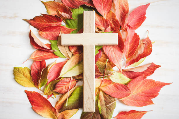 istock Wood cross with autumn leaf border on a white background 1653124768