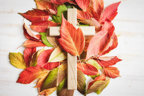 istock Wood cross with autumn leaf border on a white background 1653124791