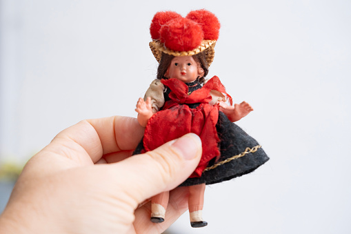 male hand holds vintage, old-fashioned German doll in national dress, Abandoned, spoiled childhood, nostalgia, puppet therapy, Loss of Innocence, heal from challenging upbringing