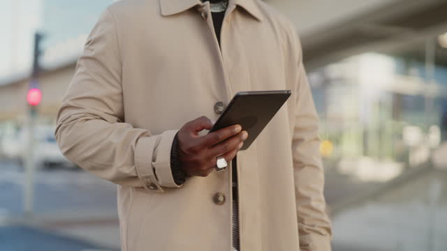Man using a digital tablet while walking, close-up on hand