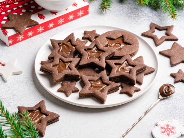 Linzer chocolate cookies on plate. Star shaped cookies with melted chocolate nutella filling. Festive christmas or new year baking. White background.