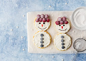 Snowman pancakes and creamcheese decorated with fresh blueberry and raspberry on ceramic plate. Christmas breakfast. Above table view. Copy space.