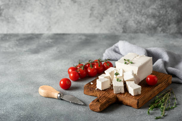 istock Feta cheese cut into cubes on a wooden board, gray concrete background. Side view, selective focus. 1653215455
