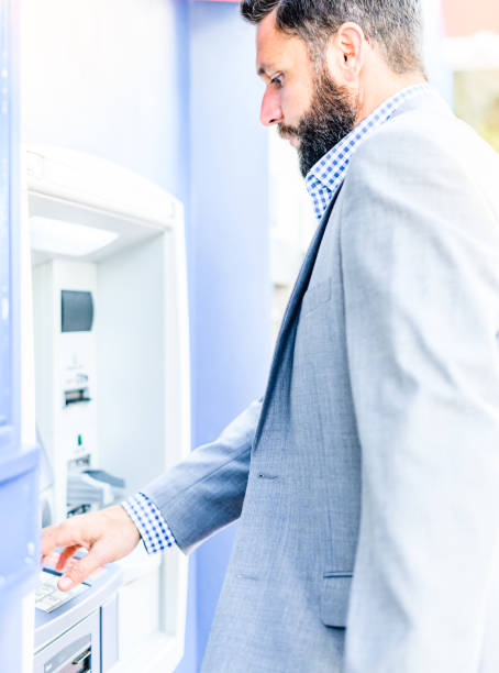 istock Well dressed business man in a suit uses an ATM 1653296036