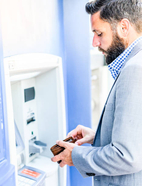 istock Well dressed business man in a suit uses an ATM 1653296039