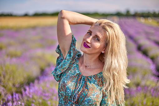 Young beautiful woman sits on a vintage swing in a lavender field