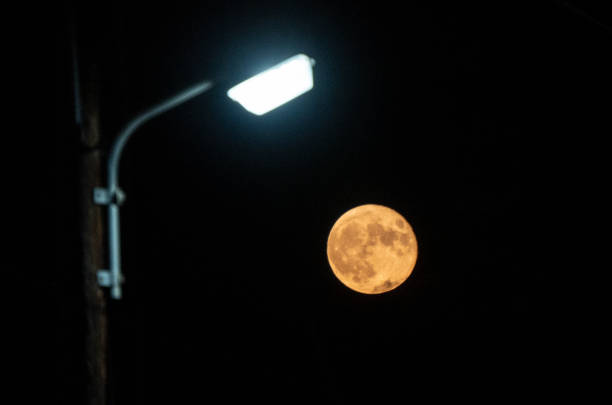 A street lamp and a full moon illuminate the street at midnight during a super moon in Greece