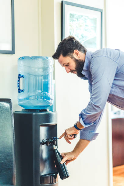 istock Man refills his reusable water bottle at a water cooler in an office 1653317010