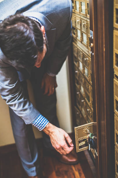 istock Man in a suit collects mail from a business or apartment complex mailbox using a key 1653327869