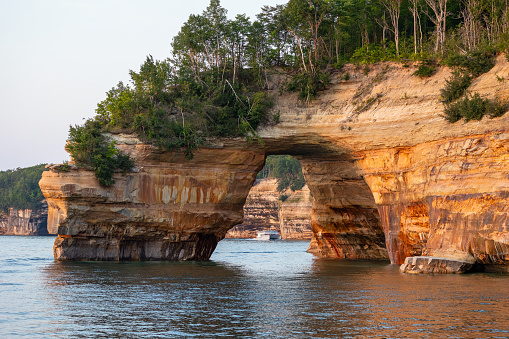 Munising, MI - August 8 2023: Catamaran filled with tourists along Pictured Rocks National Lakeshore as viewed through a natural arch