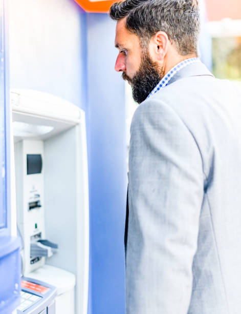 istock Banking business man in a suit uses an ATM 1653362450