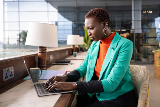 Focused young Black businesswoman using laptop in lounge