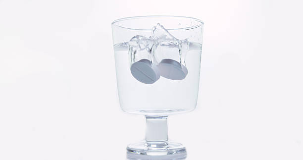 istock Tablets Falling and Dissolving into a Glass of Water against White Background 1653370919