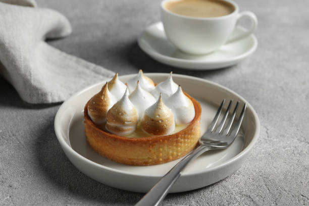 тарталетка с безе подается на светло-сером столе, крупным планом. вкусный десерт - lemon meringue pie pie pastry crust portion стоковые фото и изображения