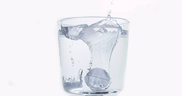 istock Tablets Falling and Dissolving into a Glass of Water against White Background 1653375280