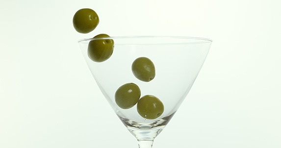 Olive Falling into a Glass against White Background