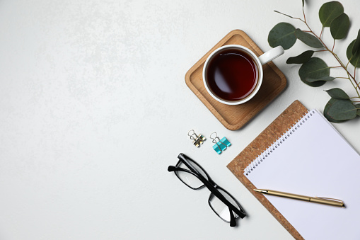 Flat lay composition with ceramic mug of aromatic tea and eucalyptus branch on white background. Space for text